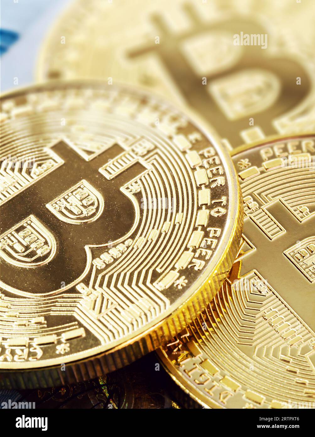 monete elettroniche bitcoin, con una banconota da cento dollari sullo sfondo. Svalutazione del real brasiliano contro la valuta decentrata. Foto Stock