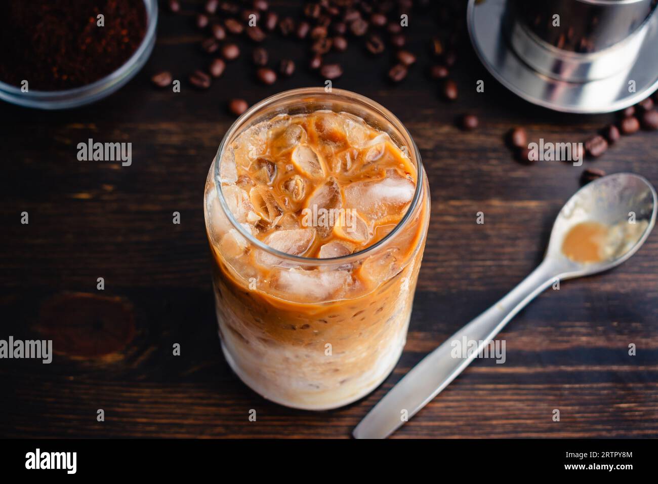 Caffè yogurt vietnamita (sua Chua Cafe o Cà Phê Sữa): Un bicchiere di caffè vietnamita ghiacciato con yogurt strained con un cucchiaio e filtro phin Foto Stock