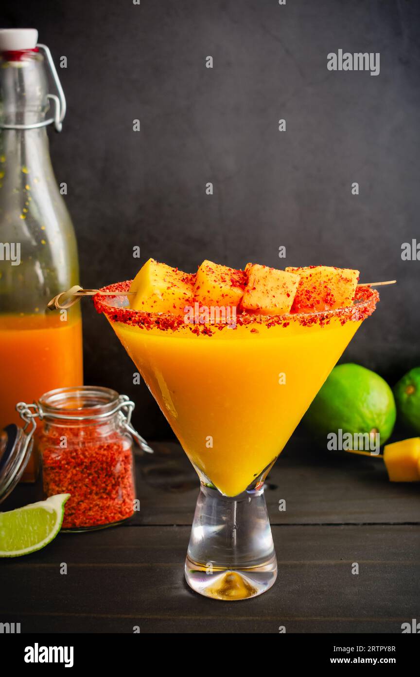 Margarita mango con torsione di peperoncino curcuma e guarnigione di mango: Cocktail mescolato con margarita curcuma mango con un bordo condito con peperoncino-lime Foto Stock