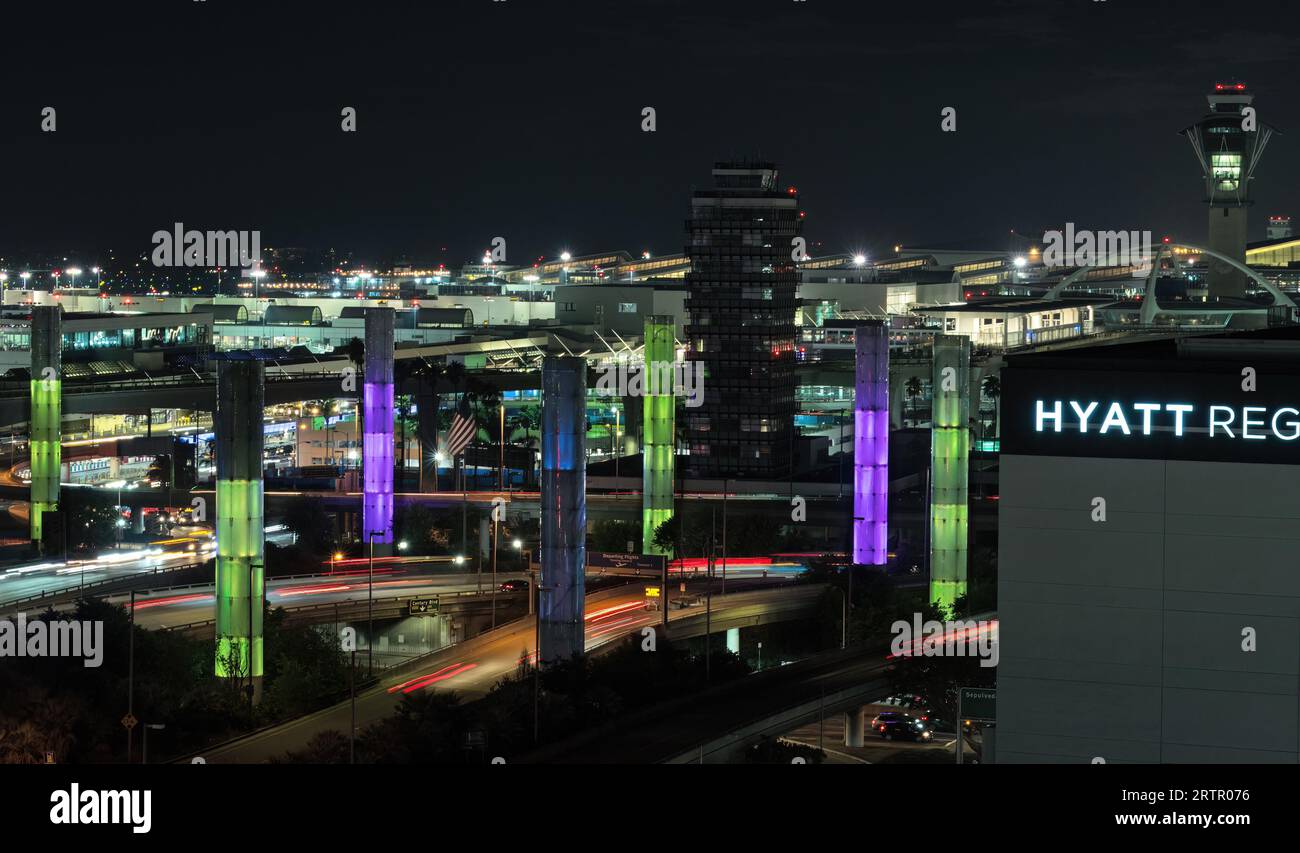 Aeroporto internazionale di Los Angeles, scena notturna, guardando a ovest. I piloni luminosi cinetici gateway di LAX sono mostrati in primo piano. Foto Stock