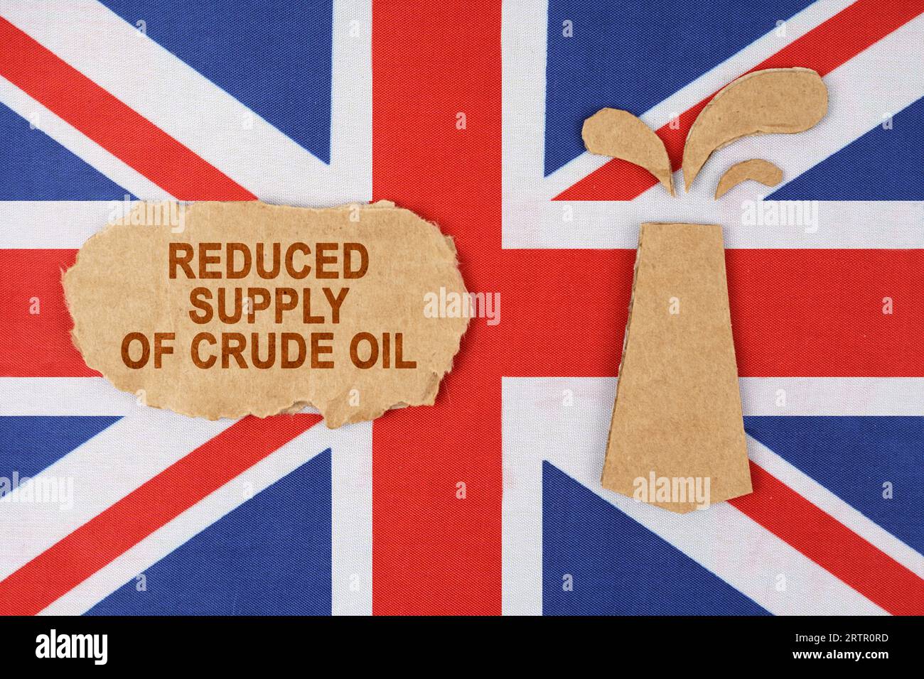 Sulla bandiera della Gran Bretagna c'è una piattaforma petrolifera tagliata di cartone e un cartello con l'iscrizione - riduzione dell'offerta di petrolio greggio. Foto Stock