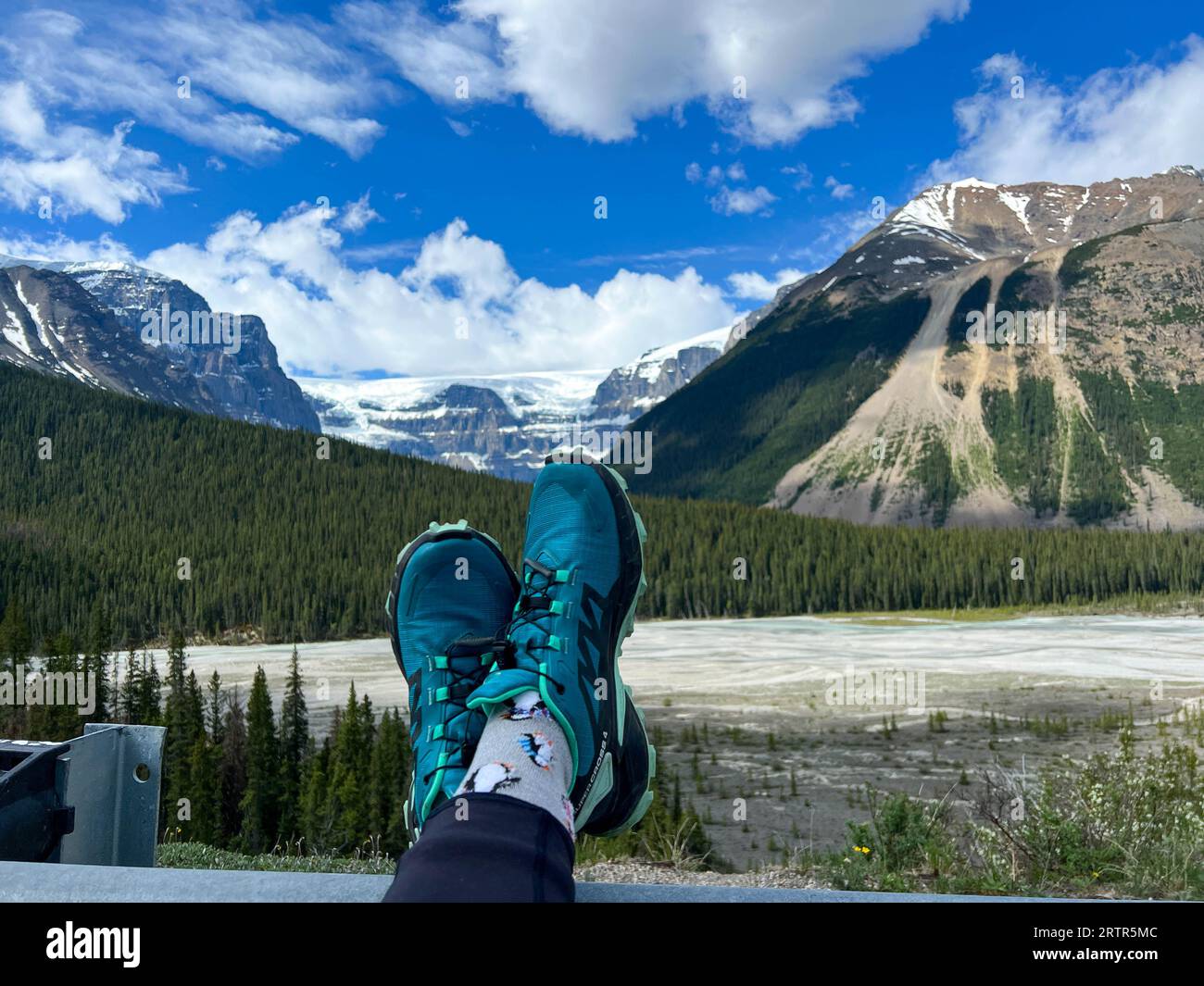 Le persone con i piedi in alto ammirano la vista panoramica del fiume Athabasca e delle montagne circostanti nel Jasper National Park, in Canada, in una splendida posizione Foto Stock