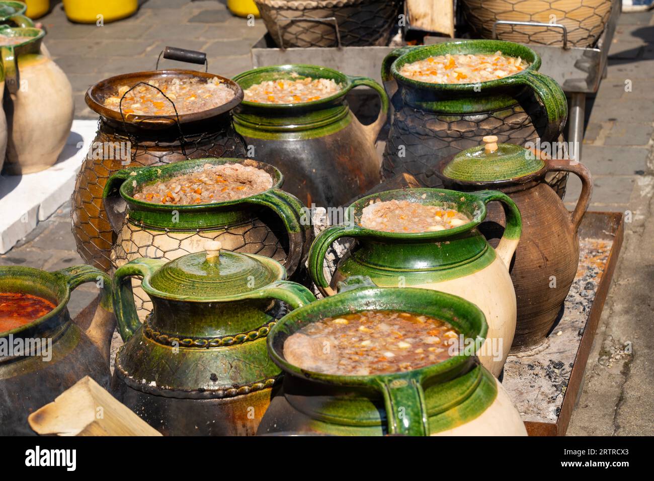 Gulasch ungherese cucinato in pentole di argilla verde-marrone da un fuoco all'aperto Foto Stock