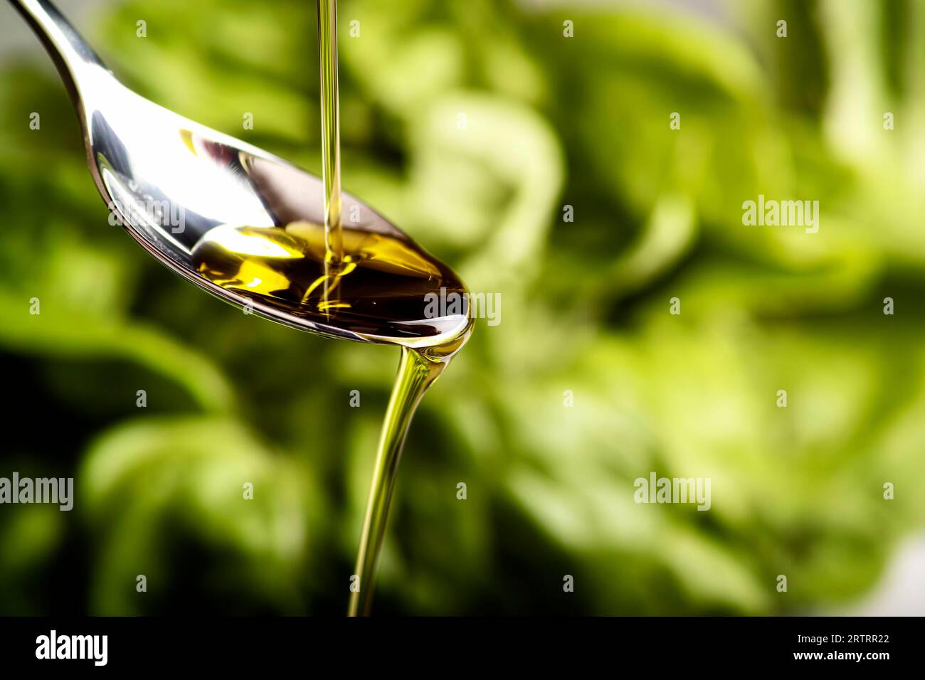 L'olio d'oliva scorre su un cucchiaio Foto Stock