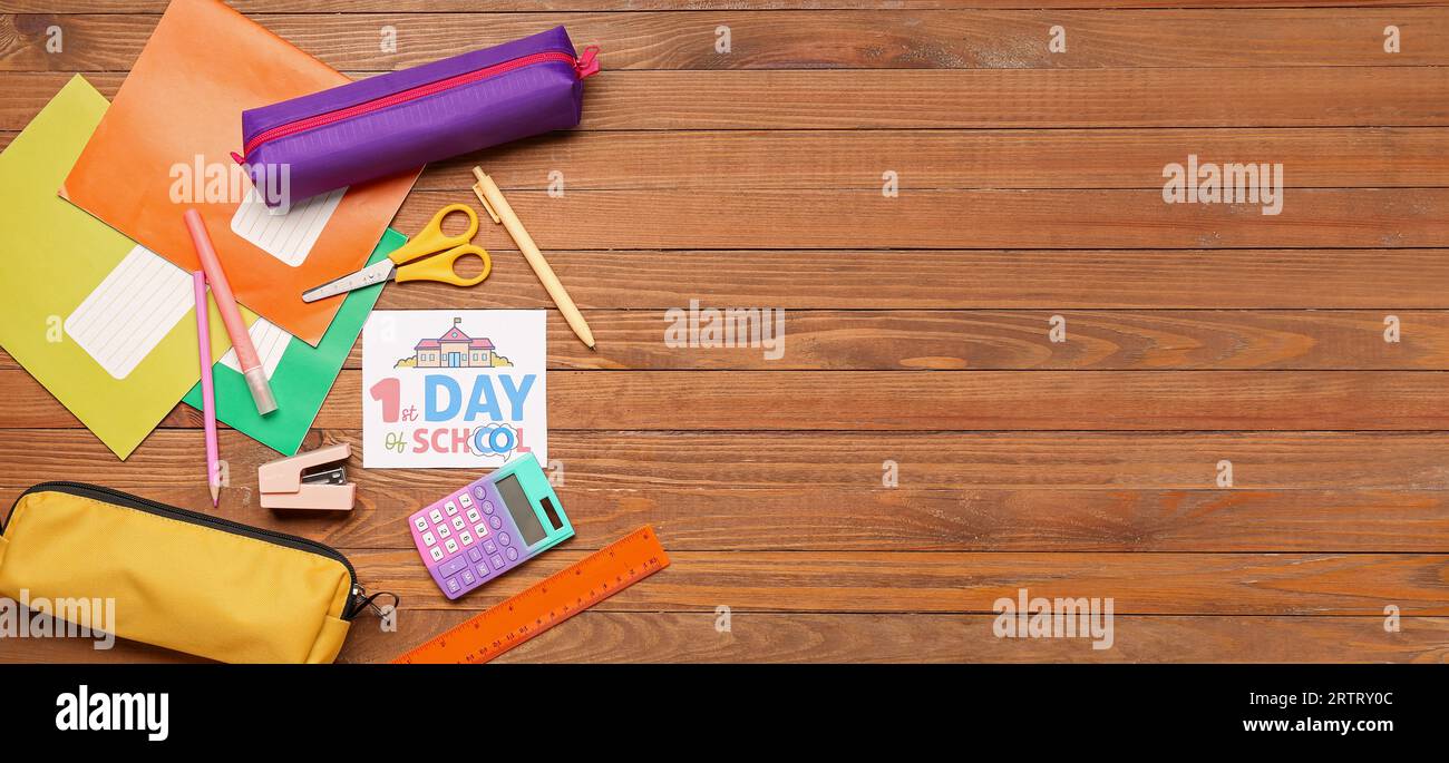 Foglio di carta con testo 1° GIORNO DI SCUOLA, calcolatrice e cancelleria diversa su sfondo di legno con spazio per il testo Foto Stock