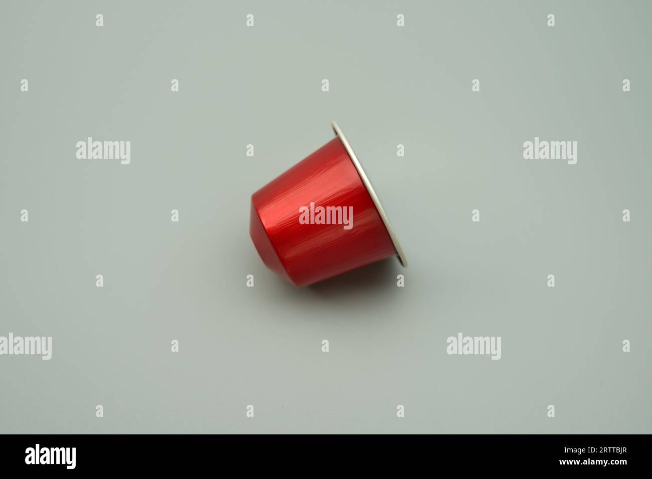 Una cialda di caffè in capsule di alluminio rossa su sfondo grigio Foto Stock