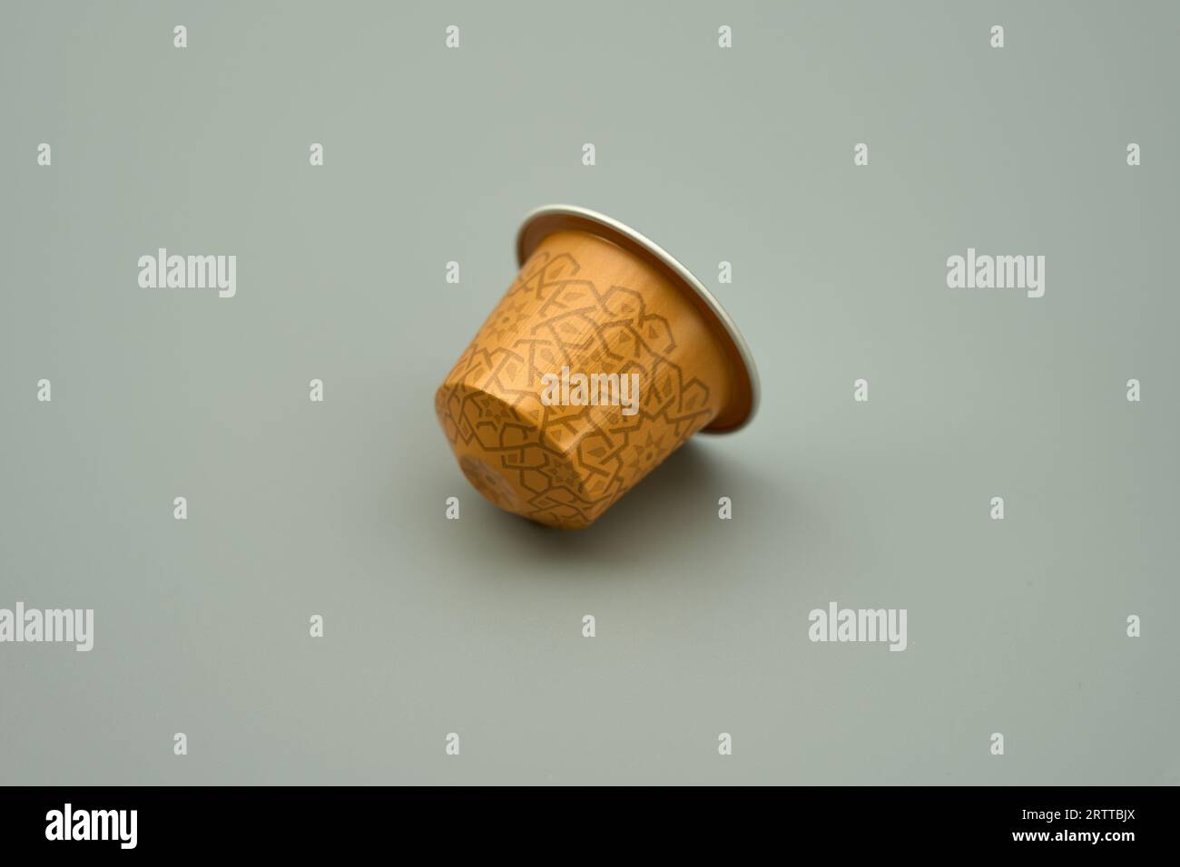 Una cialda di caffè in capsule di alluminio dorato su sfondo grigio Foto Stock