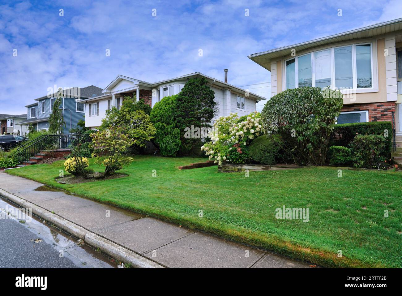 Strada suburbana americana con grandi case indipendenti con prati frontali Foto Stock