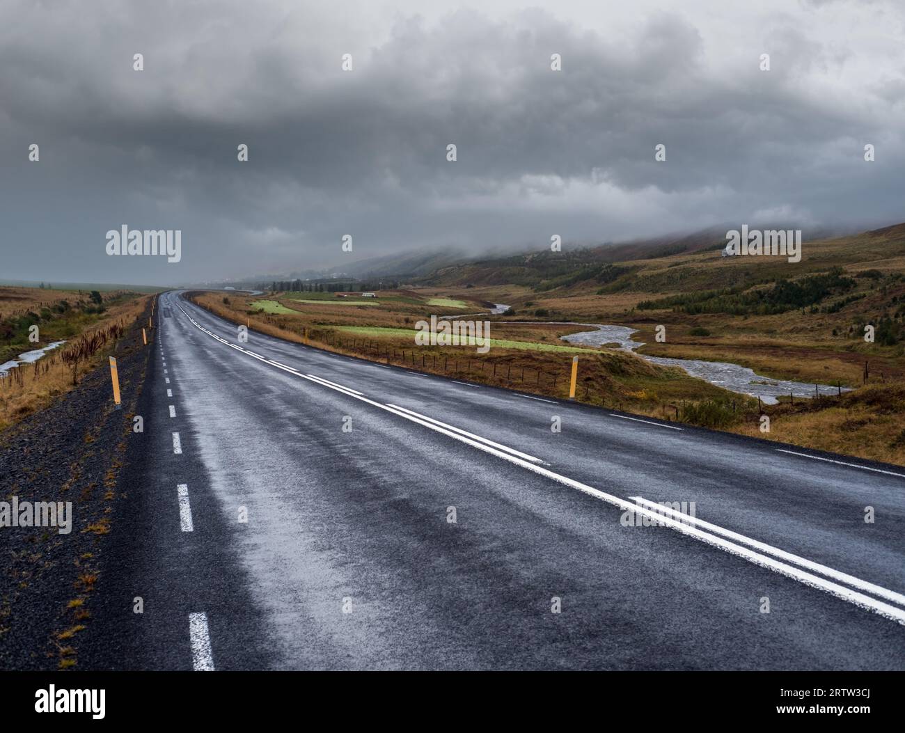 Vista sulla strada e sulle montagne durante il viaggio in auto in Islanda. Spettacolare paesaggio islandese con una natura panoramica: Montagne, campi, nuvole, g Foto Stock