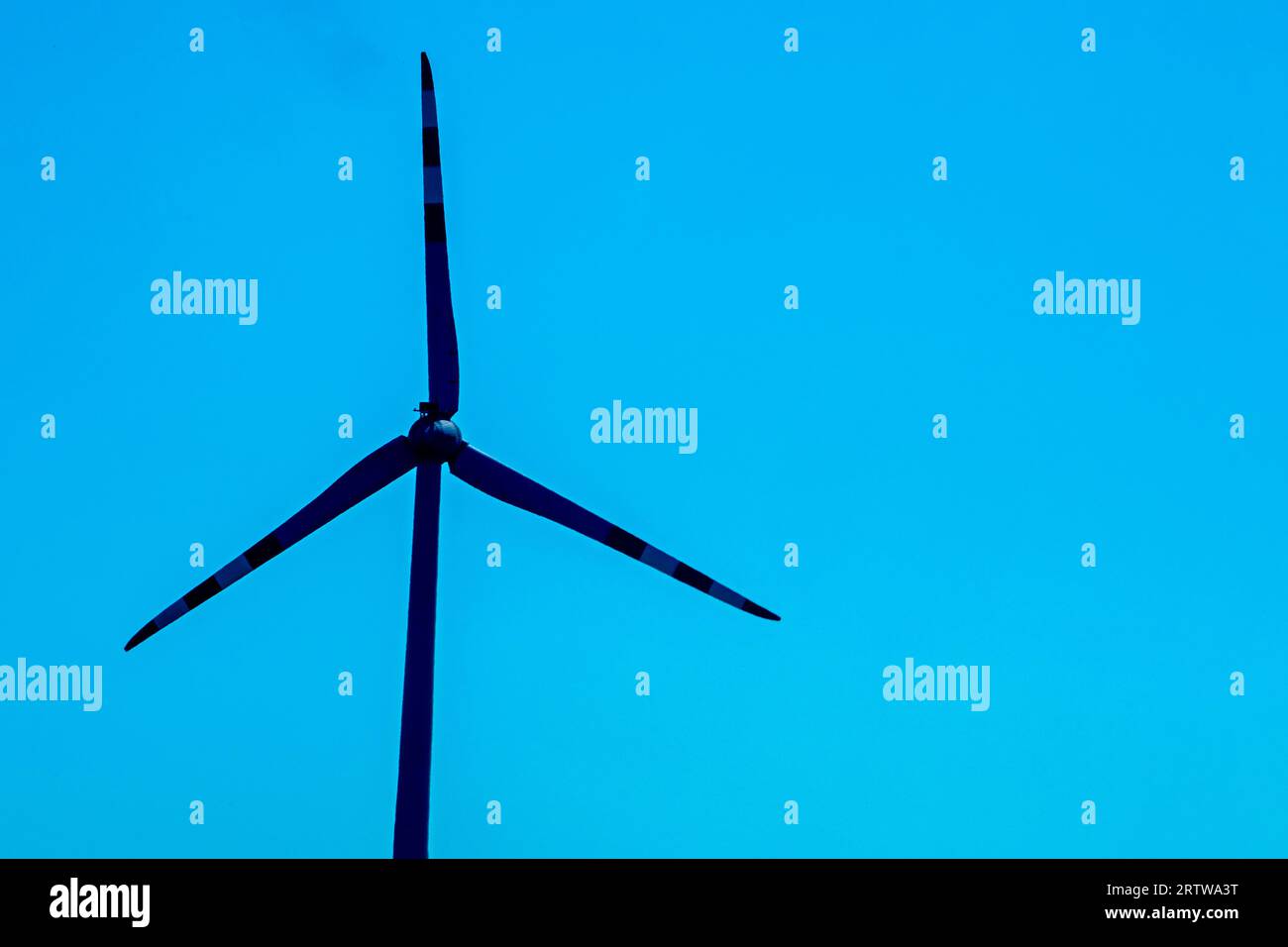 silhouette di un mulino a vento sul cielo blu. Crisi economica Foto Stock