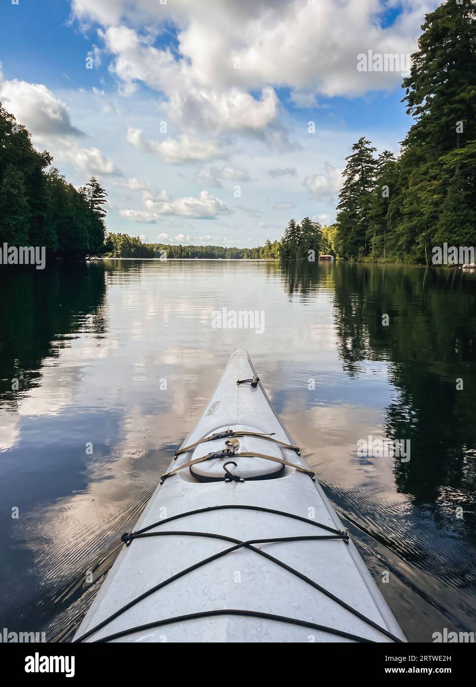 Vista del lago calmo e della parte anteriore del kayak dalla prospettiva del pagaiatore. Foto Stock