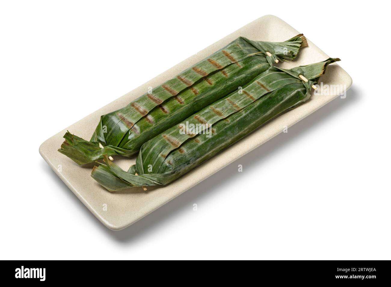 Lemper fresco alla griglia avvolto in foglie di banana, uno spuntino salato indonesiano fatto di riso glutinoso ripieno da vicino in un piatto, isolato su sfondo bianco Foto Stock
