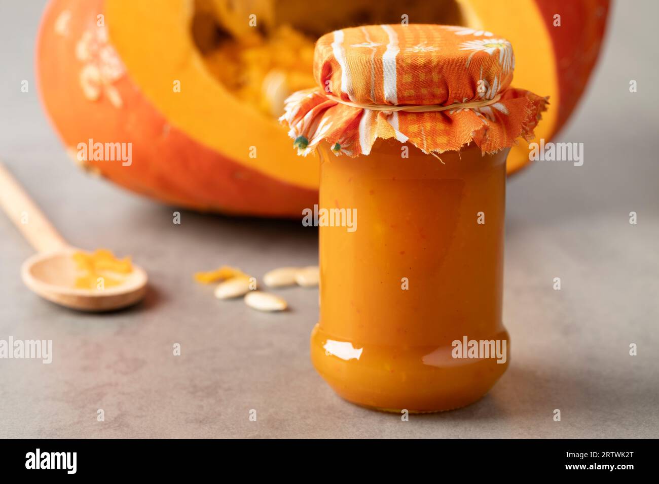 Vaso di vetro con marmellata di zucca arancione fatta in casa da vicino davanti a una zucca fresca Foto Stock