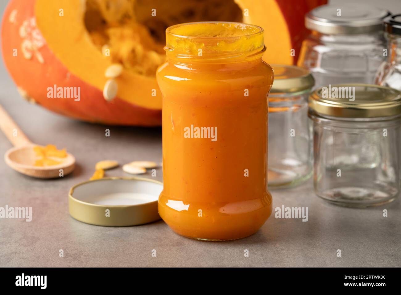 Vaso di vetro con marmellata di zucca arancione fatta in casa da vicino davanti a una zucca fresca Foto Stock