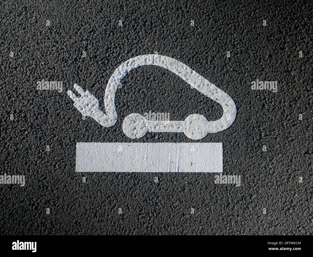 Icona del caricabatteria per veicoli elettrici su asfalto, concetto di richiesta elevata di punti di ricarica EV, carica della batteria elettrica, parcheggio Foto Stock