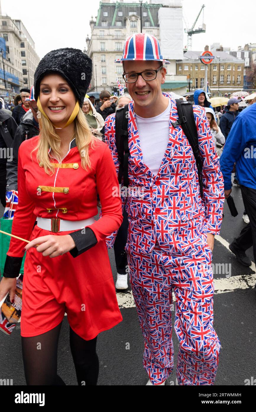 Un uomo che indossa un costume Union Jack cammina giù Piccadilly sotto la pioggia, parte della grande folla che si dirige a guardare l'incoronazione di re Carlo III. Piccadilly, Foto Stock