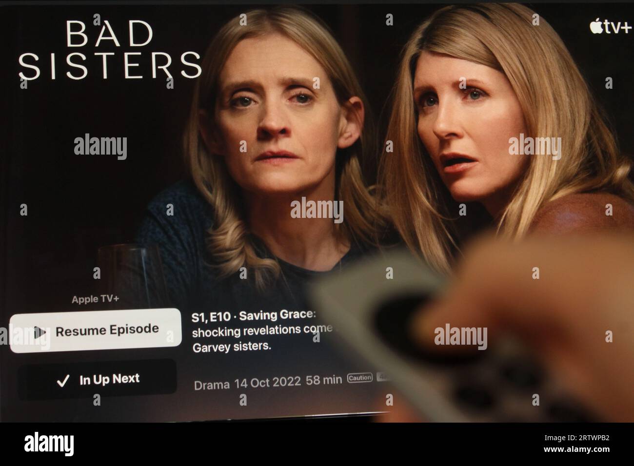 App Apple TV+ sullo schermo tv che evidenzia la serie televisiva Bad Sisters con l'ombra di qualcuno che tiene davanti un telecomando Apple TV. Foto Stock