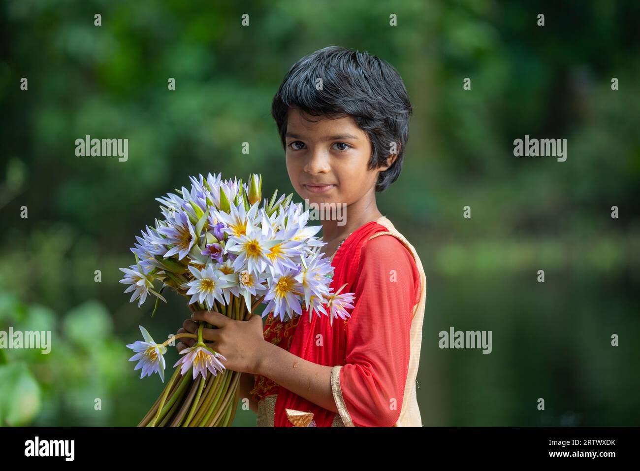 Una ragazza bengalese tiene in mano un mucchio di ninfei d'acqua che formano un grande corpo d'acqua chiamato "Shatla beel" a Ujirpur a Barisal. Bangladesh. Foto Stock