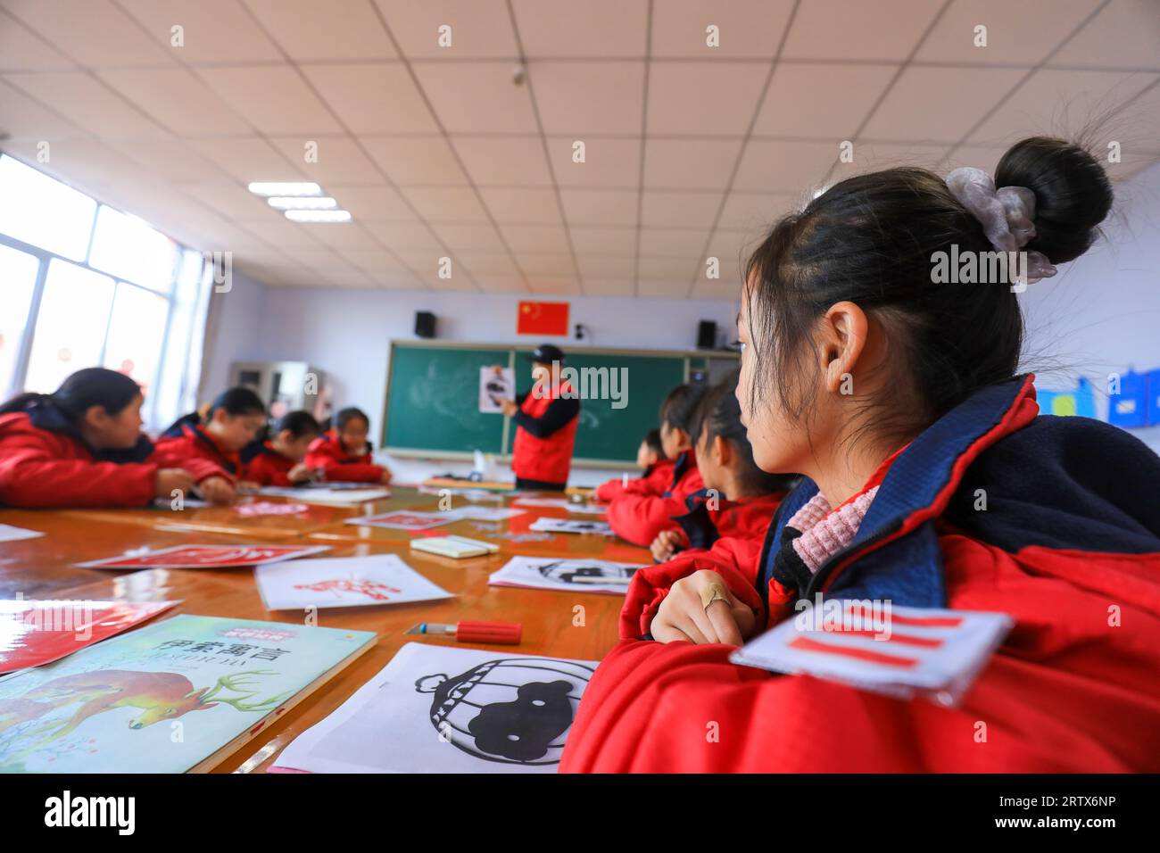 CONTEA DI LUANNAN, Cina - 10 dicembre 2021: Gli studenti delle scuole elementari imparano la tradizionale arte cinese del taglio della carta sotto la guida degli insegnanti, North C. Foto Stock