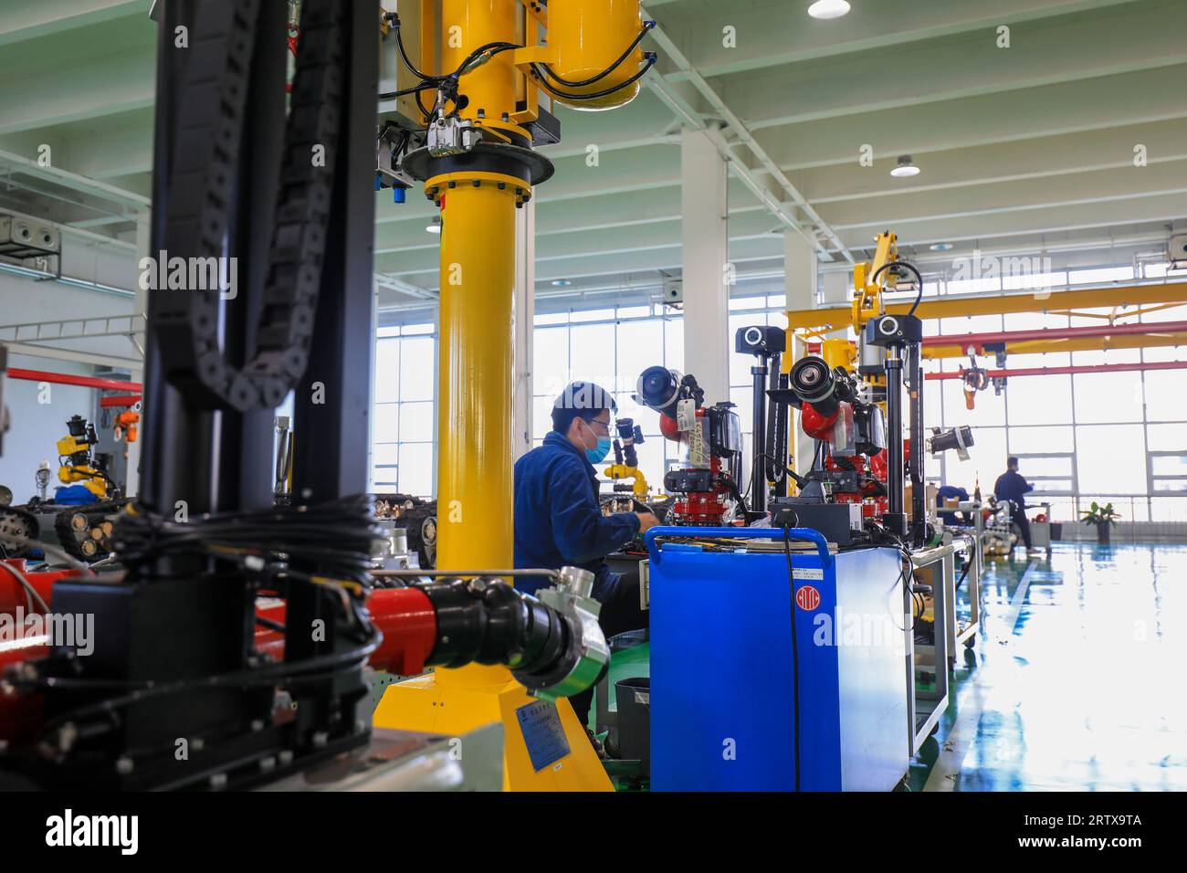 Tangshan, Cina - 16 dicembre 2021: I lavoratori lavorano duramente sulla linea di produzione di robot antincendio, Cina settentrionale Foto Stock