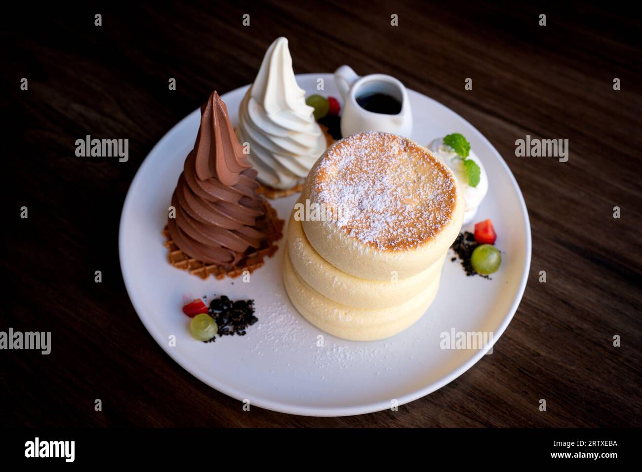 Primi piani di soffici pancake di soufflé con cioccolato e gelato alla vaniglia serviti con salsa al miele. Foto Stock