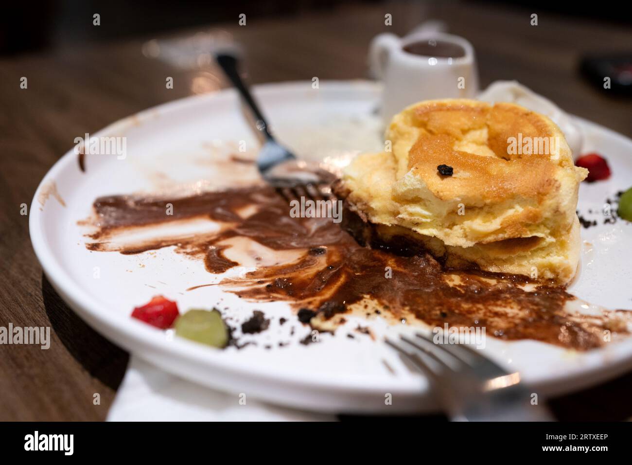 Dessert con frittelle di souffle e gelato al cioccolato servito su un piatto bianco su un tavolo di legno Foto Stock