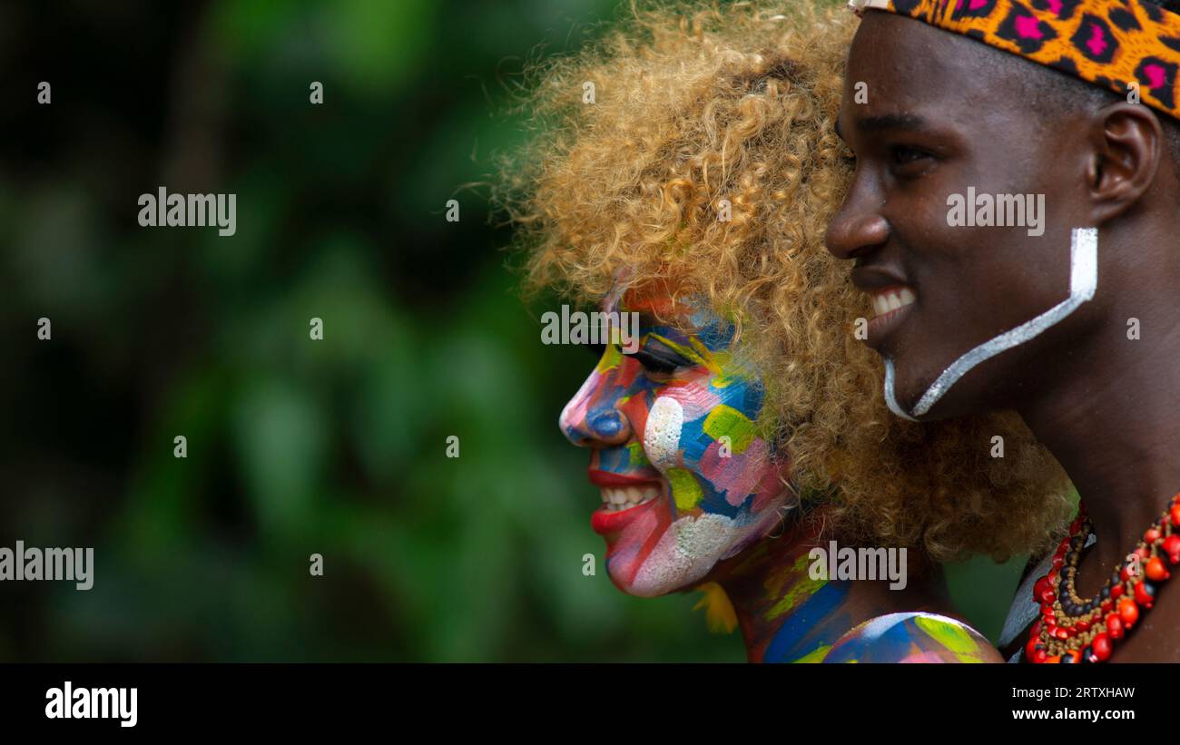 Nueva Loja, Sucumbios / Ecuador - 3 settembre 2020: Ritratto di profilo di una giovane coppia nera con volti colorati dipinti che abbracciano e sorridono in primo piano Foto Stock