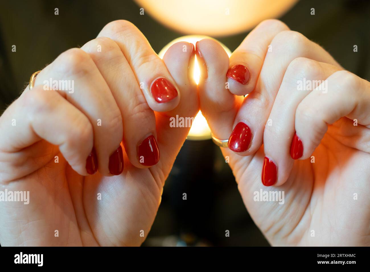 Prova delle dita in ghisa, prova della finestra di Schamroth. Donna che si spinge le unghie del pollice insieme mostrando un vuoto luminoso e superando il test. Vernice per unghie rossa. Foto Stock