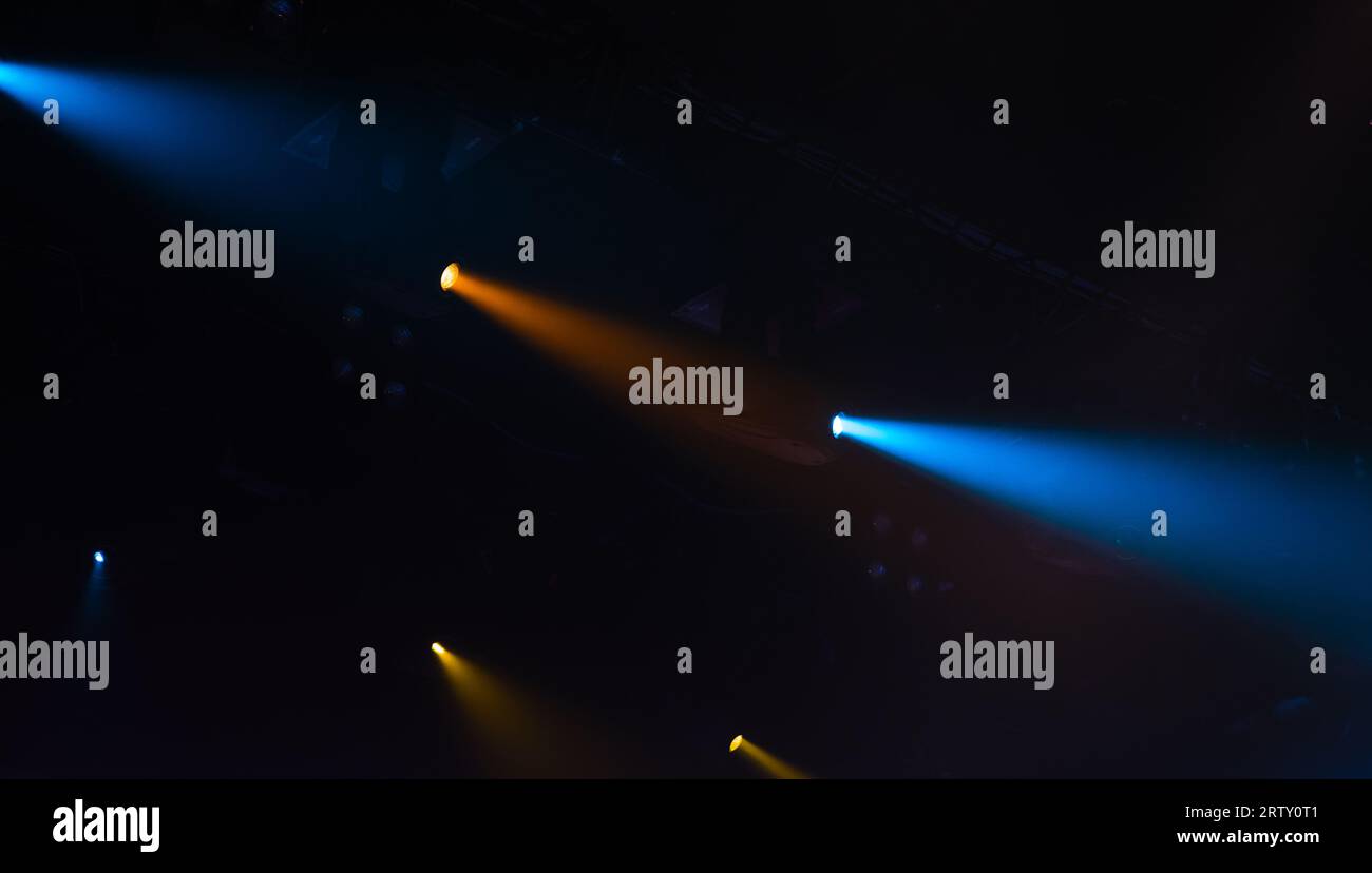 Luci spot panoramiche, fasci blu e gialli sono in fumo su sfondo scuro e illuminazione moderna del palcoscenico Foto Stock