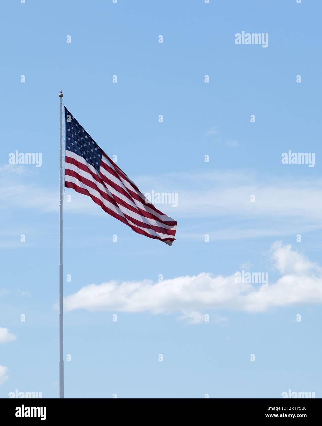 Grande bandiera degli Stati Uniti su un'asta alta contro un cielo blu con nuvole bianche Foto Stock