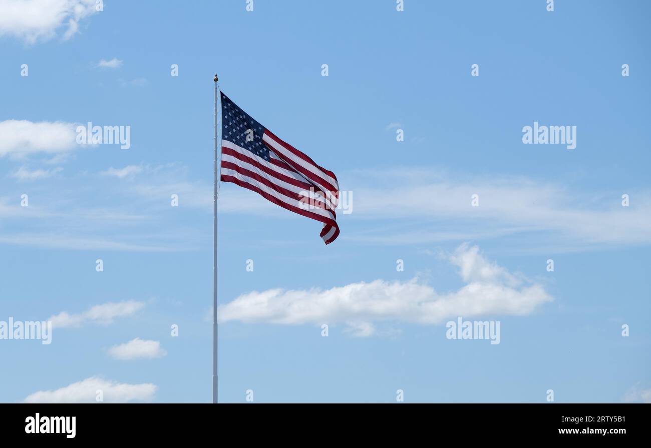 Grande bandiera degli Stati Uniti su un'asta alta contro un cielo blu con nuvole bianche Foto Stock