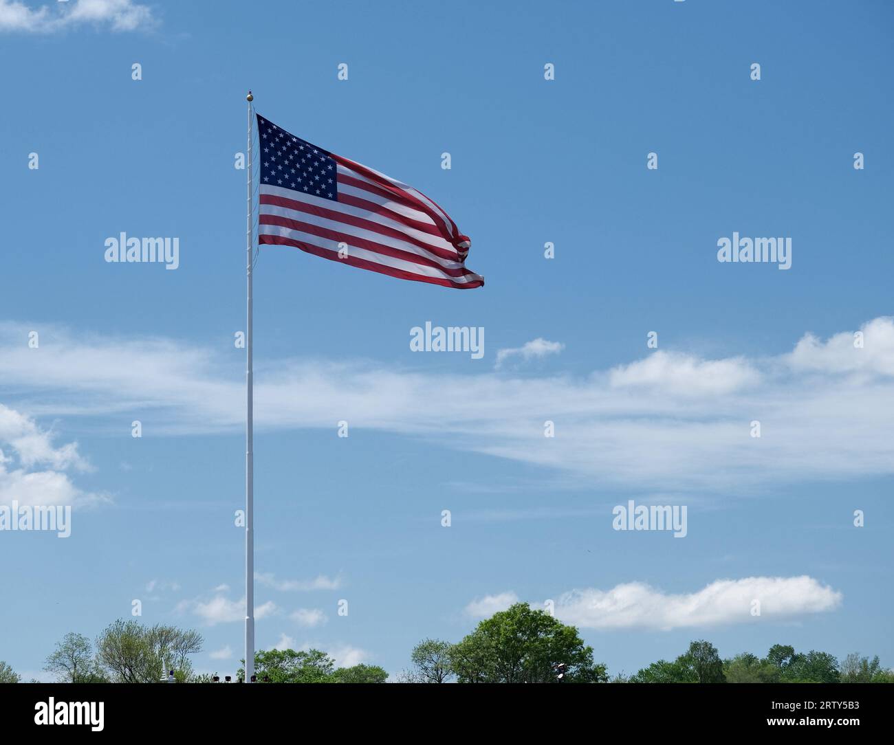 Grande bandiera degli Stati Uniti su un'asta alta contro un cielo blu con nuvole bianche Foto Stock