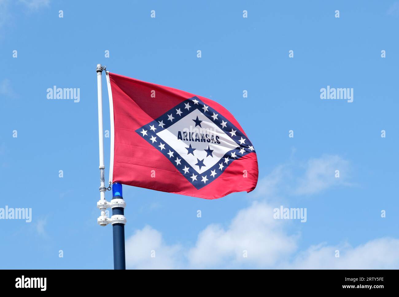 Foto ravvicinata della bandiera dello stato dell'Arkansas che sventola su uno sfondo blu con nuvole bianche Foto Stock