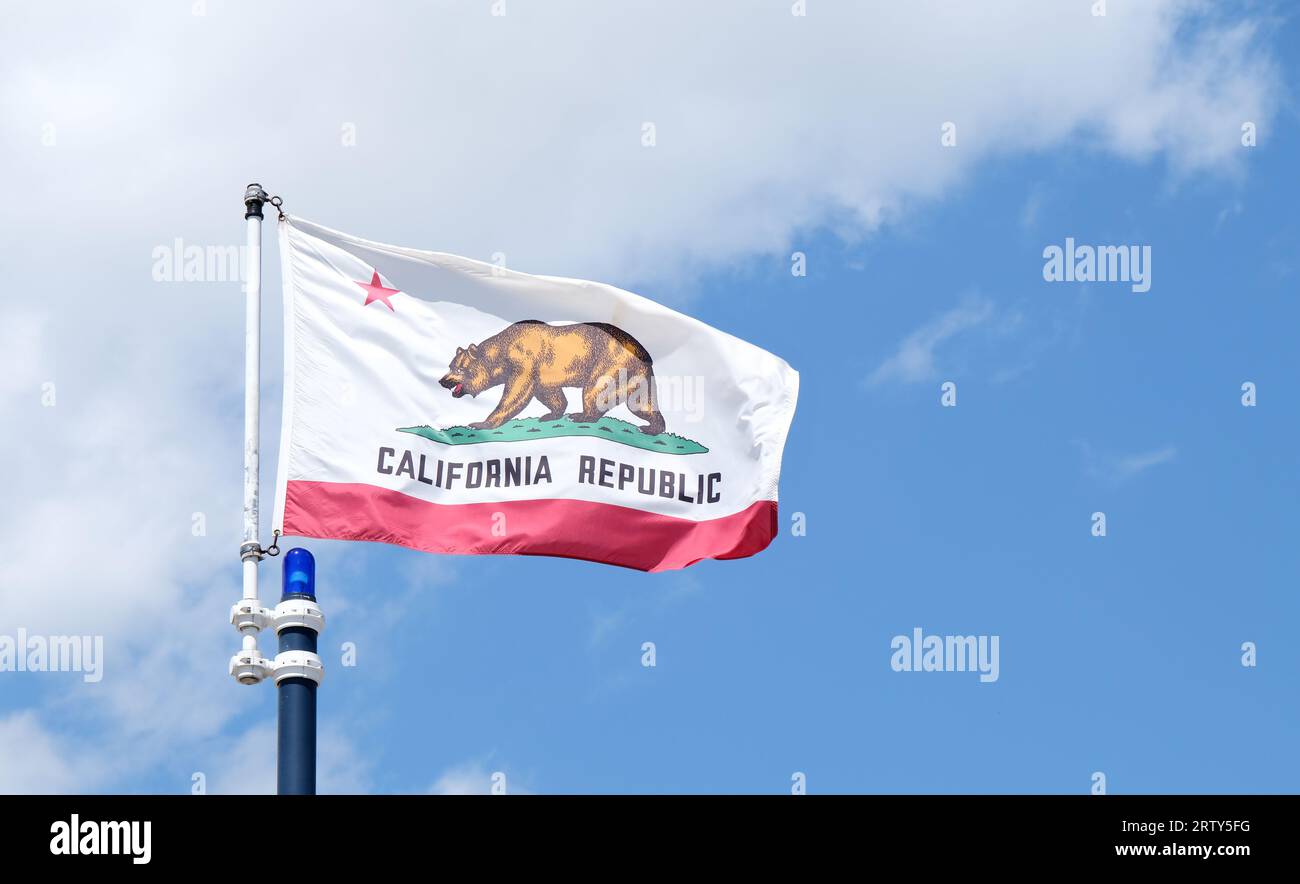Bandiera dello stato della California che sventola su uno sfondo blu con nuvole bianche Foto Stock