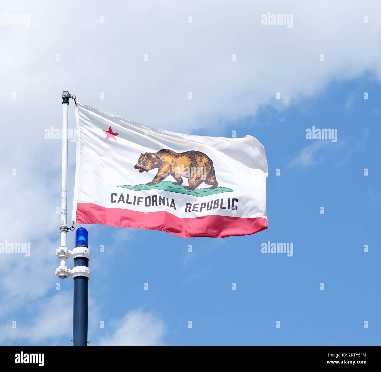Bandiera dello stato della California che sventola su uno sfondo blu con nuvole bianche Foto Stock
