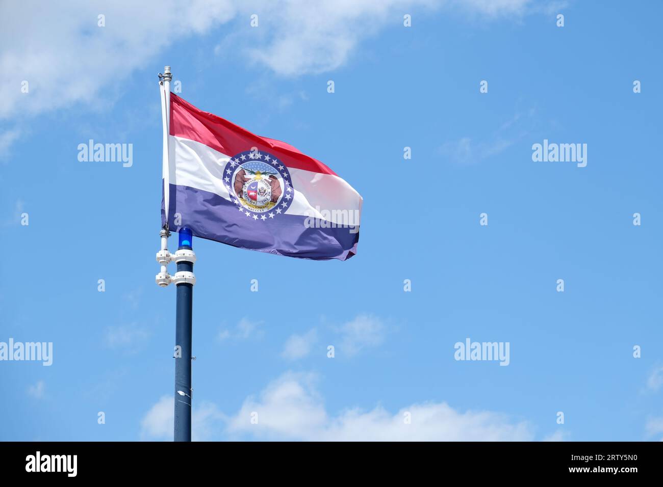 Primo piano della bandiera dello stato del Missouri su sfondo blu cielo e nuvole bianche Foto Stock