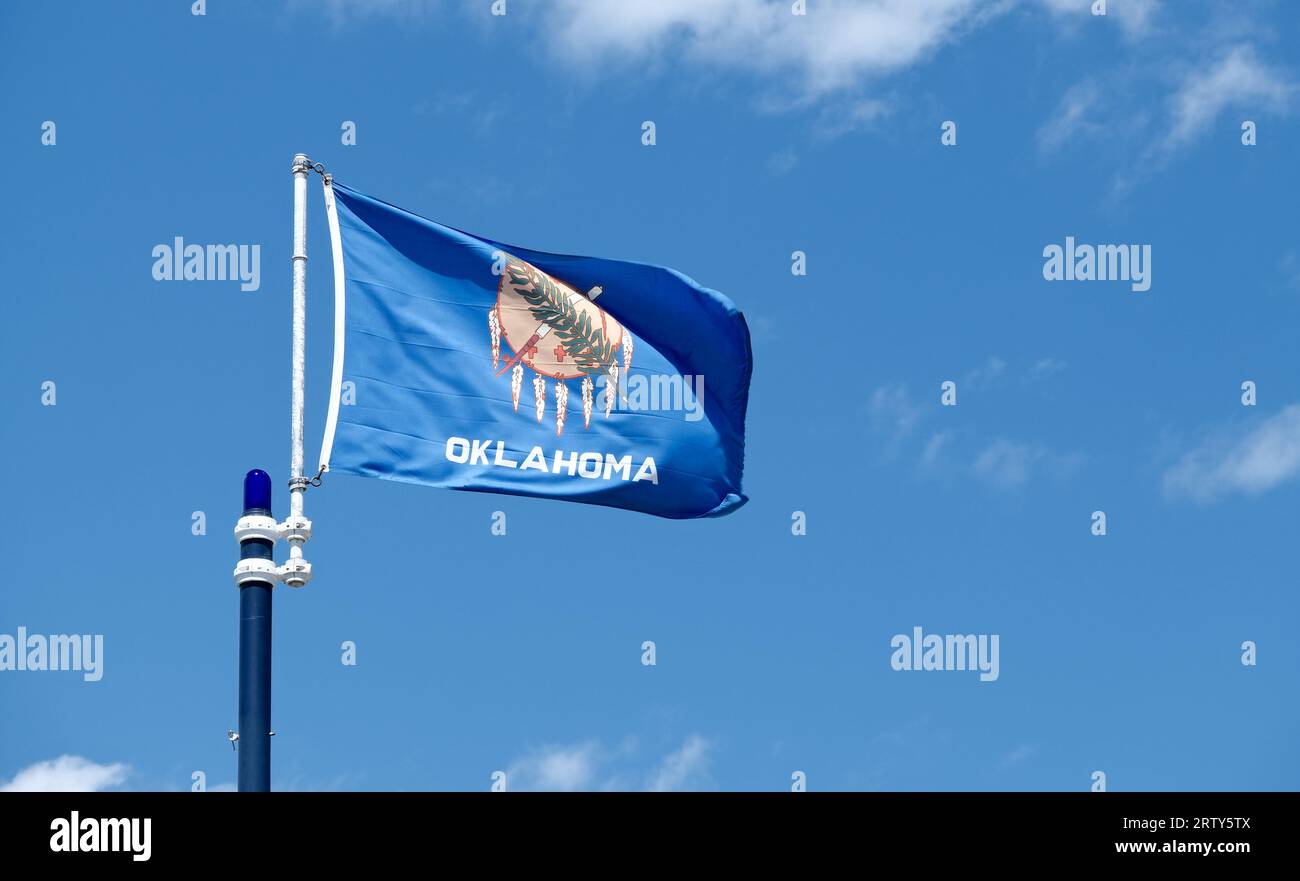 Primo piano della bandiera dello stato dell'Oklahoma su uno sfondo blu e nuvole bianche Foto Stock