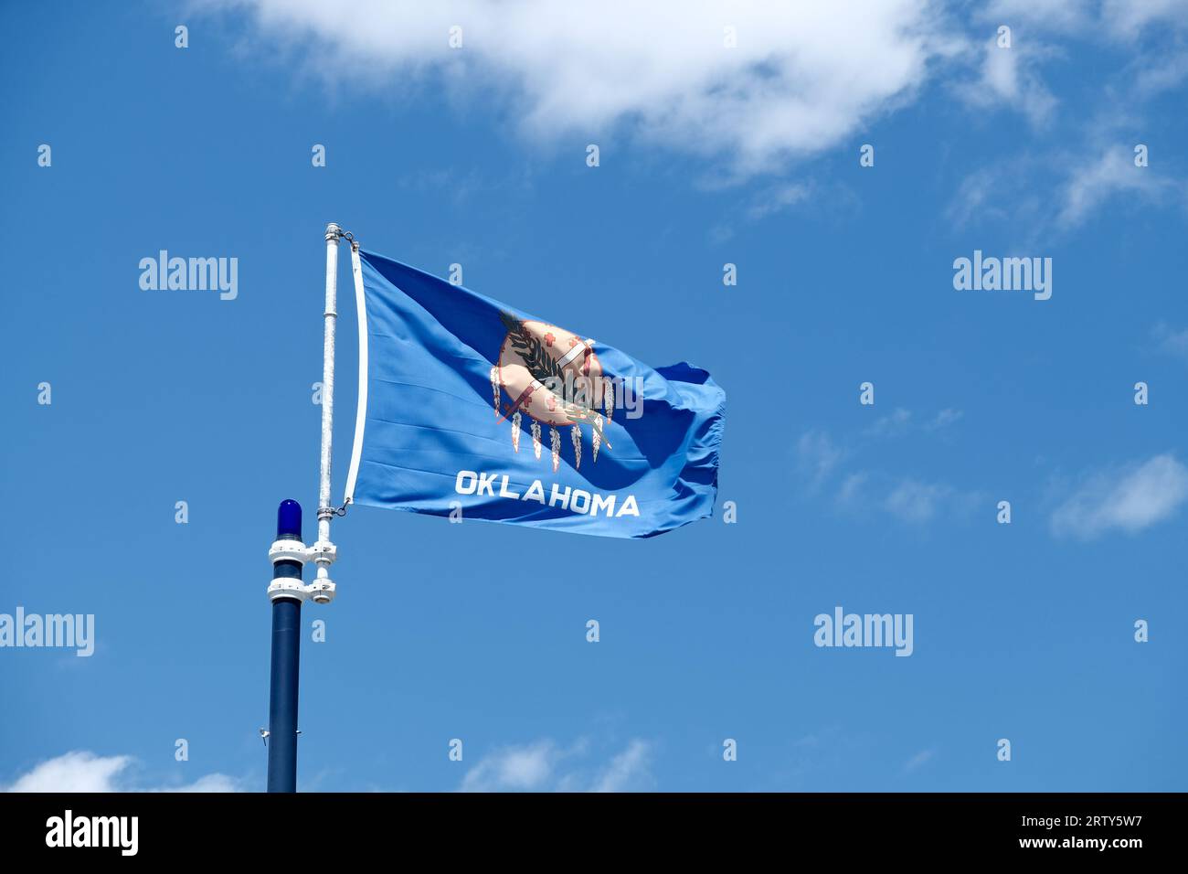 Primo piano della bandiera dello stato dell'Oklahoma su uno sfondo blu e nuvole bianche Foto Stock