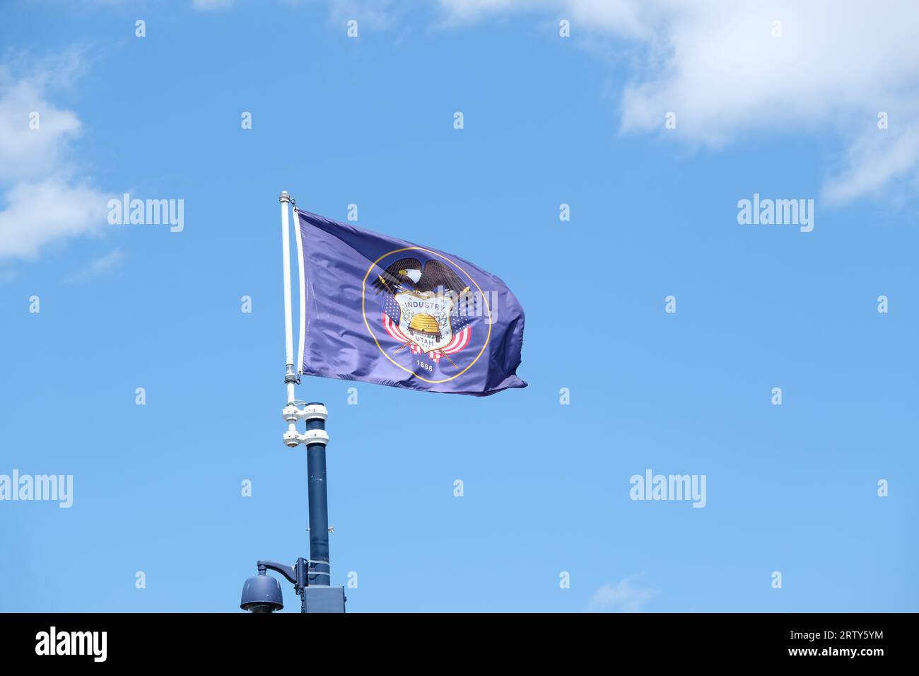 Primo piano della bandiera dello stato dello Utah su uno sfondo blu e nuvole bianche Foto Stock