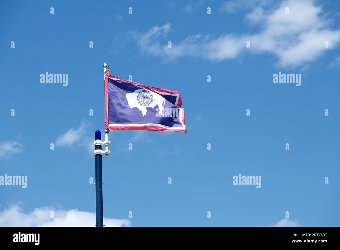 Bandiera dello Stato del Wyoming che sventola su uno sfondo blu con nuvole bianche Foto Stock