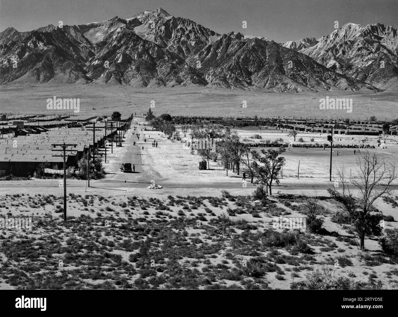 Owens Valley, California 1943 Vista da una torre di guardia del Manzanar Relocation Center, uno dei più piccoli campi di internamento per giapponesi-americani. La fotografia mostra il lato occidentale del parco con le montagne della Sierra Nevada. Al suo apice, Manzanar ha tenuto circa 10.000 detenuti, con i primi detenuti arrivati nel 1942 e l'ultimo che se ne è andato nel 1945. Oggi è conservato come sito storico nazionale. Fotografia di Ansel Adams. Foto Stock
