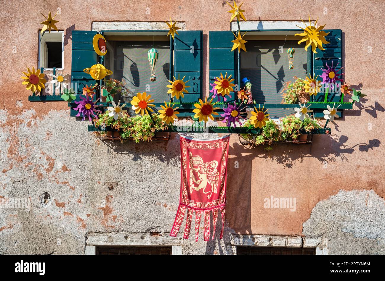 Antica finestra veneziana con decorazioni floreali e bandiera della Repubblica di Venezia. Dettaglio ravvicinato. Foto Stock