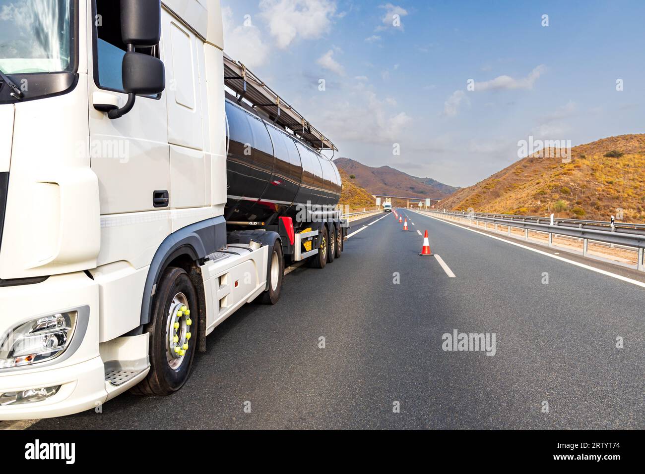 Autocisterna in avaria sull'autostrada con coni posizionati dal servizio autostradale per tagliare la corsia trafficata. Foto Stock