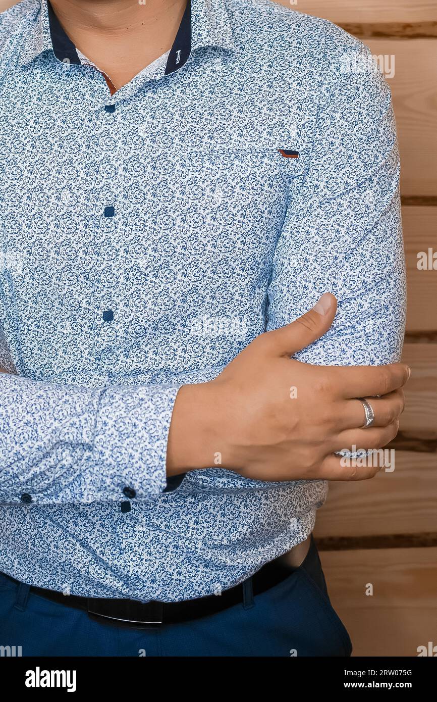 Camicia da uomo in stile business blu chiaro con motivi astratti in posa con mano su sfondo in legno. Foto Stock