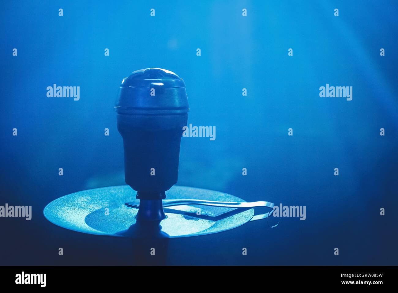 Primo piano nel recipiente per la testa del narghilè, oggetto fumante con luce blu. Foto Stock
