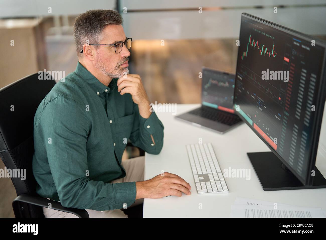 Vecchio imprenditore investitore azionario che analizza il mercato del trading di investimenti. Foto Stock