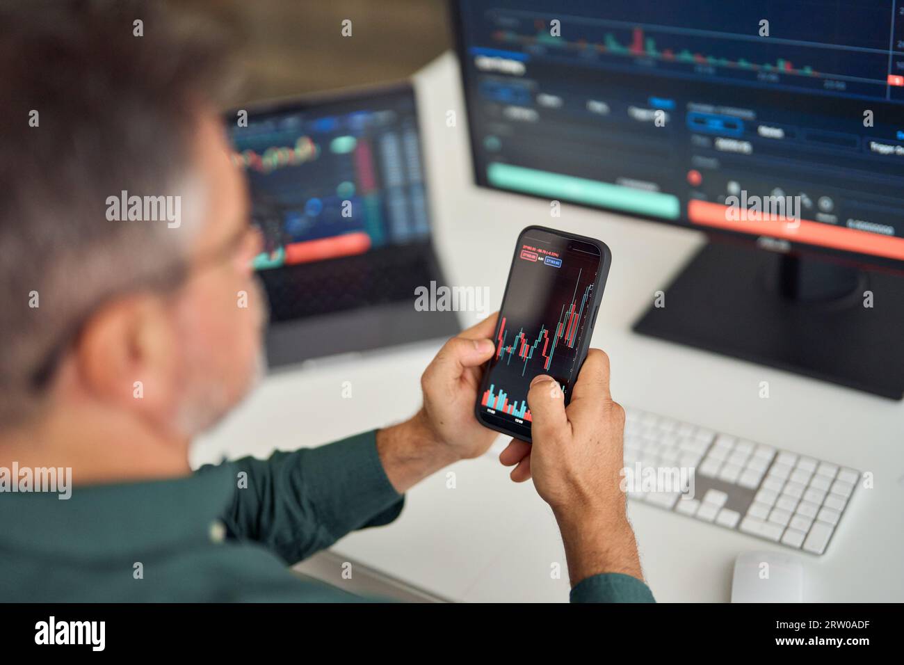 Investitore trader che analizza il mercato azionario delle criptovalute per telefono. A spalla. Foto Stock