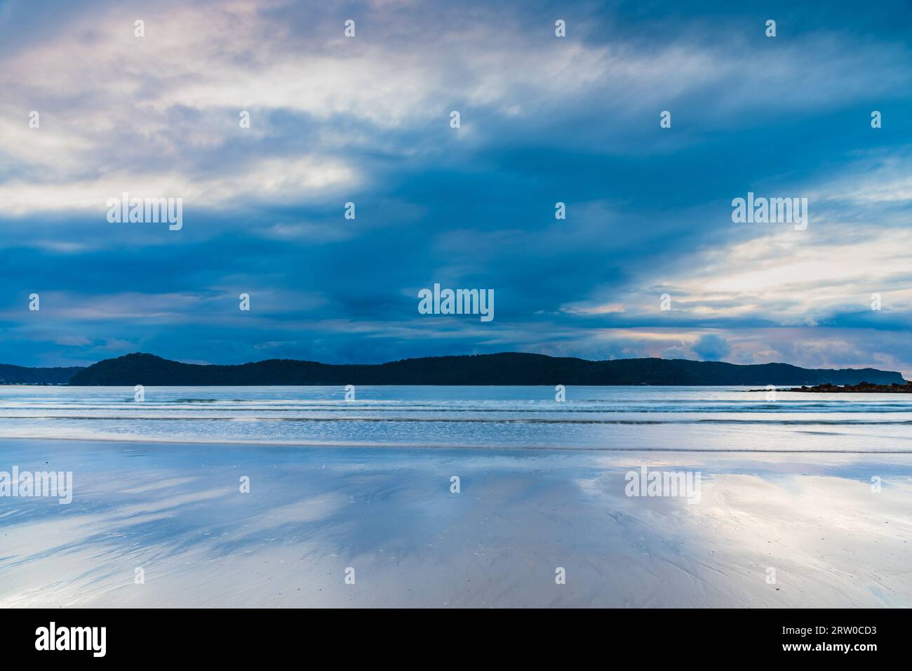 Il sole si alza con le nuvole di pioggia a Umina Point a Umina Beach sulla Central Coast, NSW, Australia. Foto Stock