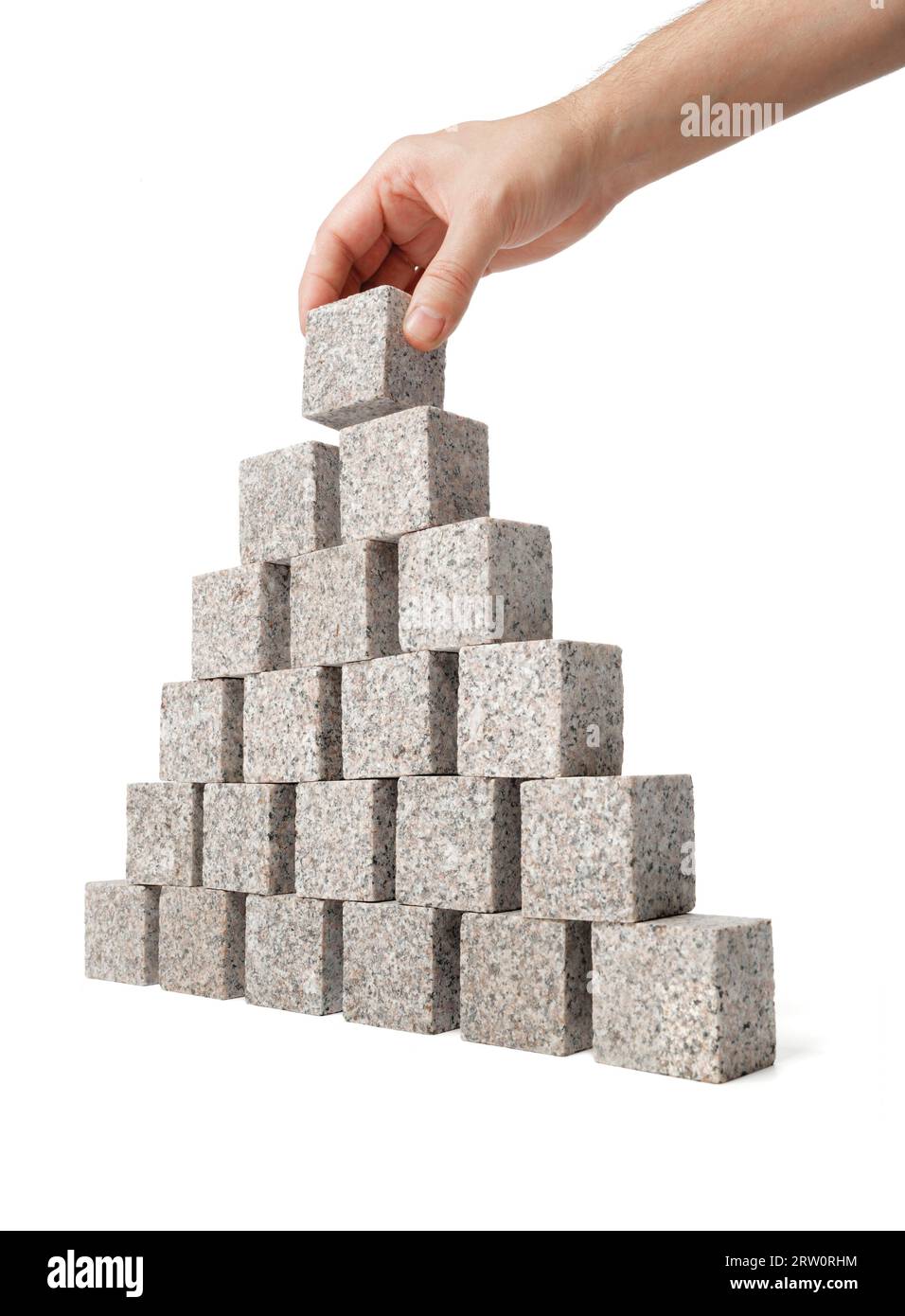 Uomo che costruisce una piramide fatta di piccoli blocchi di roccia granitica Foto Stock
