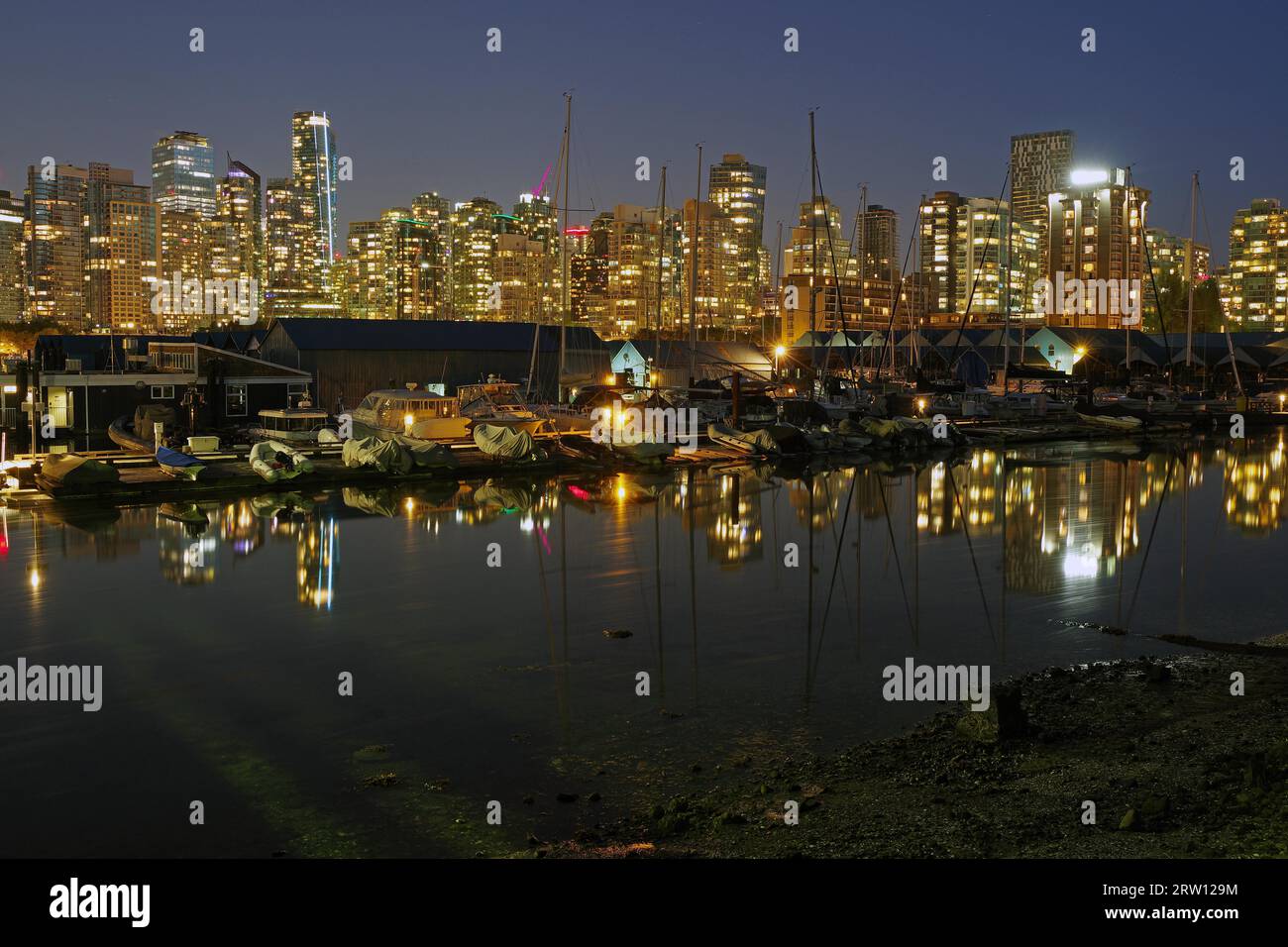 Grattacieli illuminati e barche a vela nell'ultima luce serale, riflessi d'acqua, Stanley Park, Vancouver, British Columbia, Canada Foto Stock